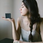 Young woman showcasing eco-friendly, handmade black soap indoors.